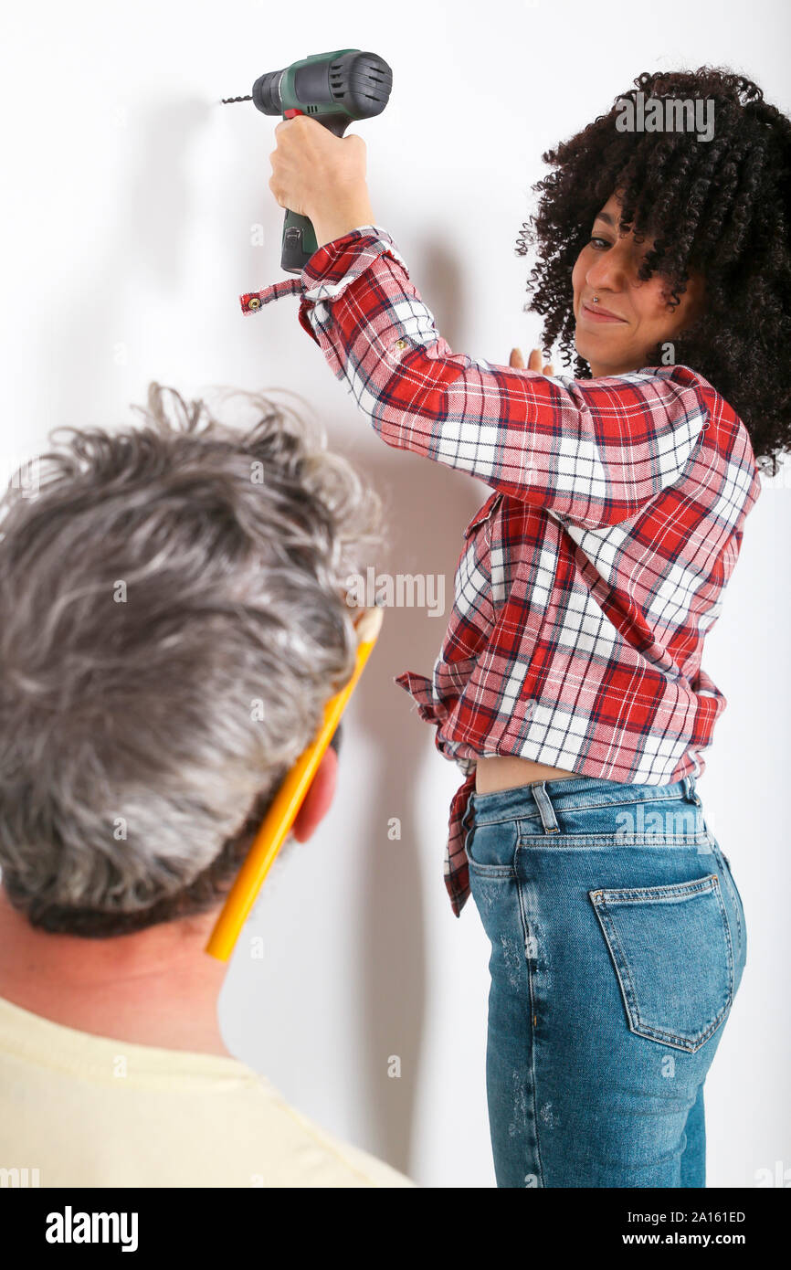Couple drilling hole in the wall at home Stock Photo