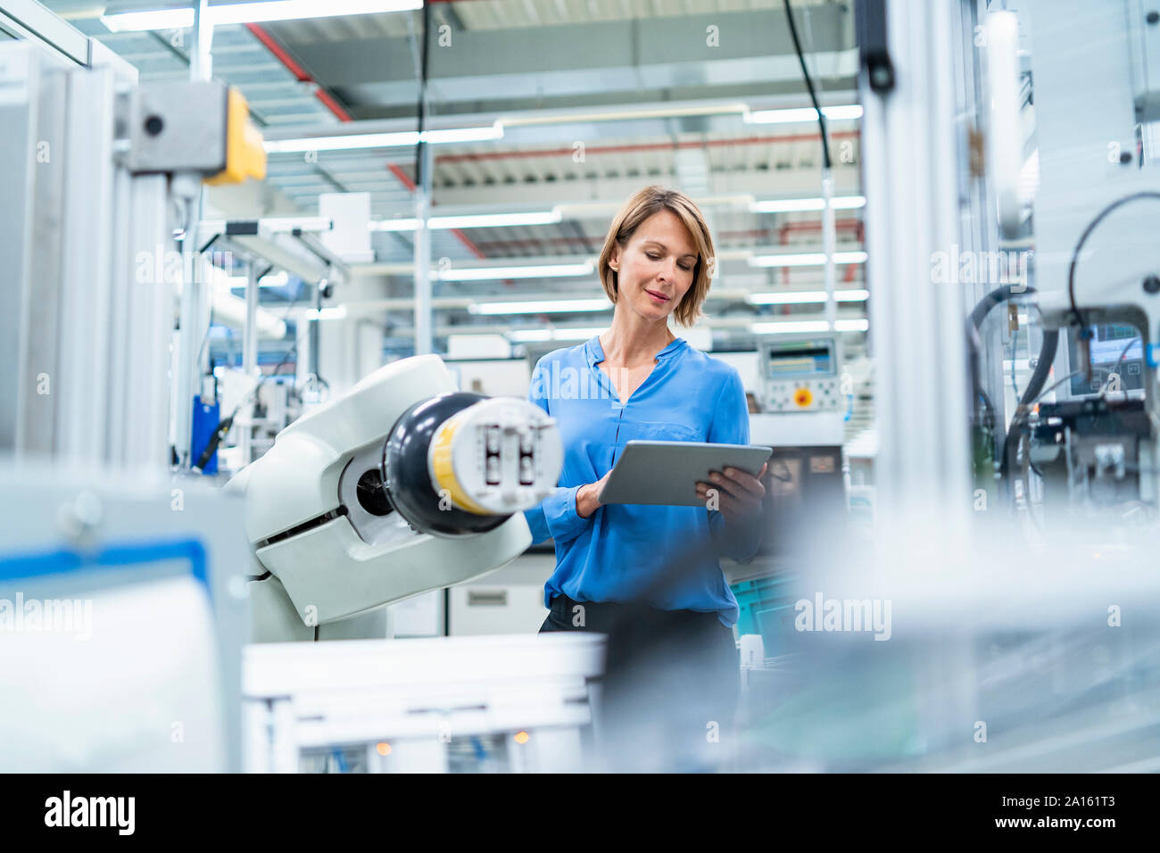 Businesswoman with tablet at assembly robot in a factory Stock Photo