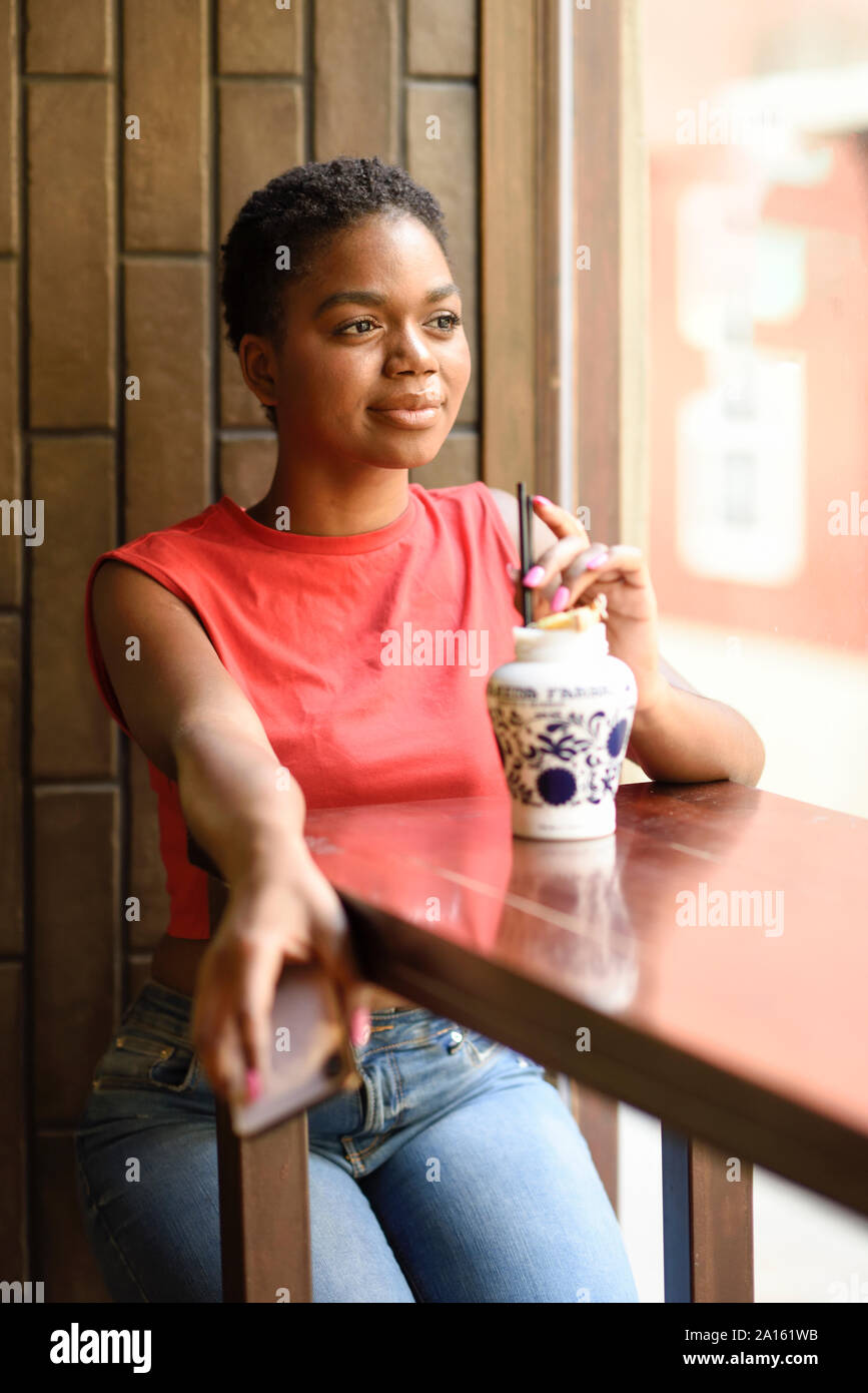 Portrait of content young woman in a bar looking out of window Stock Photo