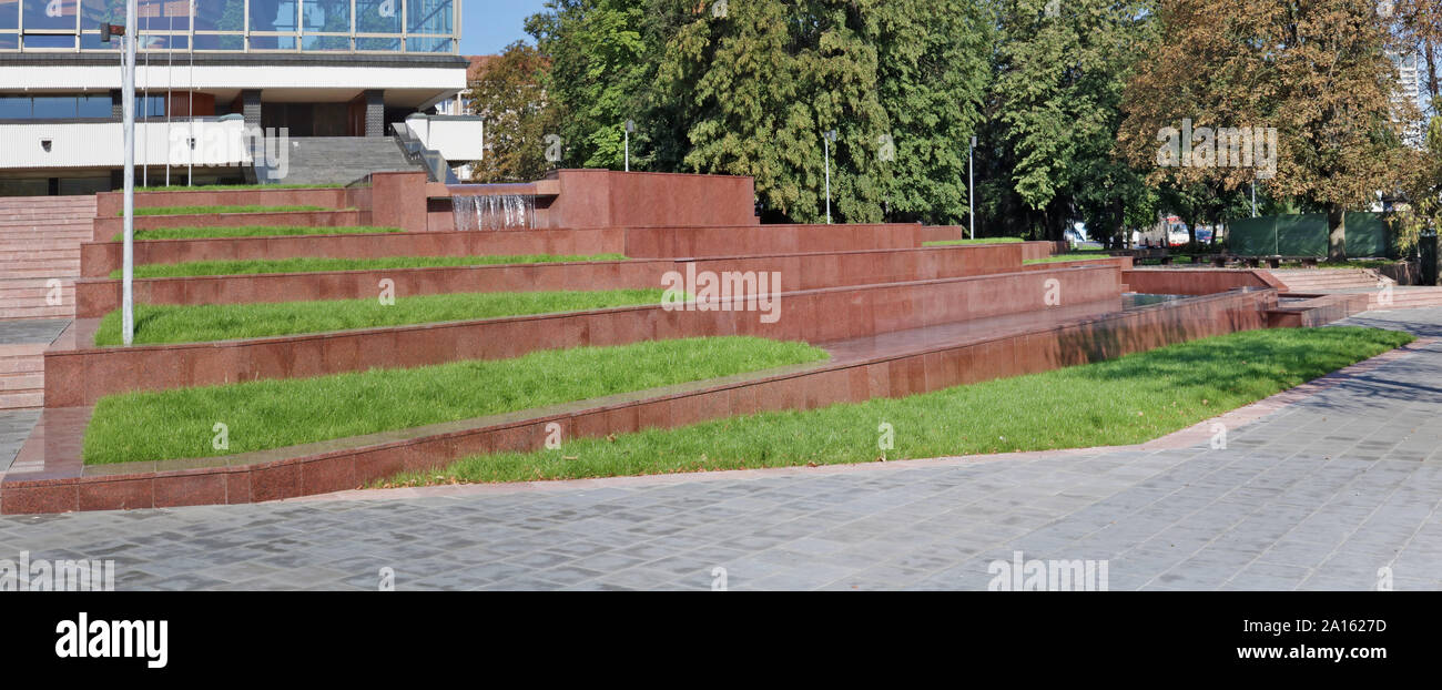 The renovated restored fountain near the public Vilnius Opera House is made of red granite. The first fountain was built 40 years ago Stock Photo