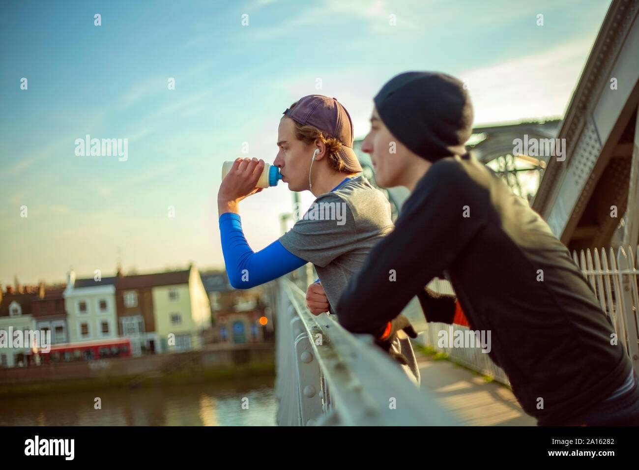Two young men drinking water after a run by River Thames, London, UK Stock Photo