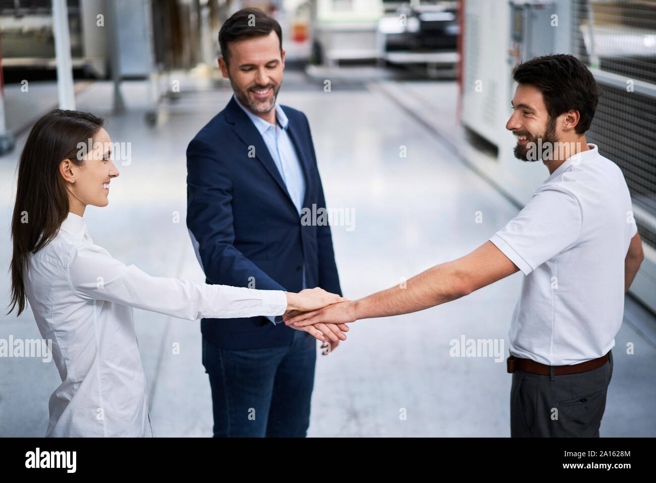 Businessman and employees stacking hands in a factory Stock Photo