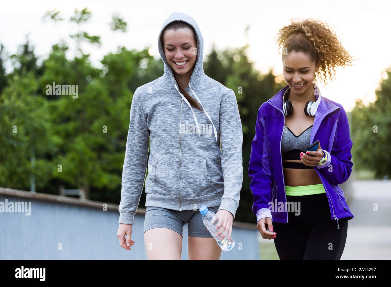 Two smiling sporty young women walking in park after workout Stock Photo