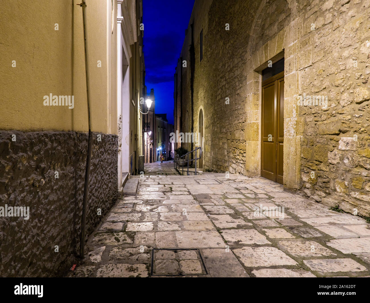 Illuminated empty alley amidst buildings in old town at night Stock Photo