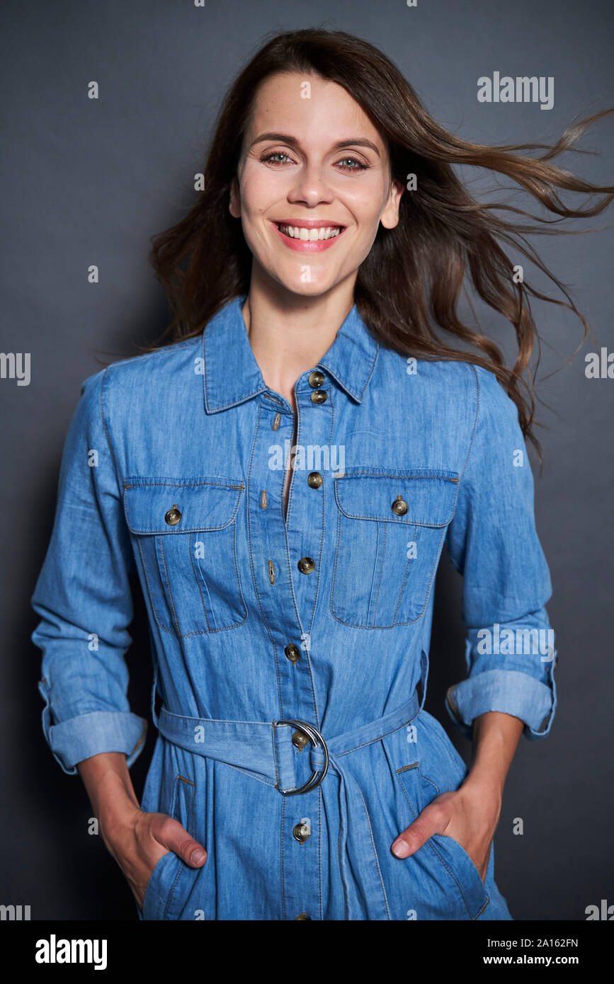 Portrait of smiling attractive woman wearing denim dress Stock Photo