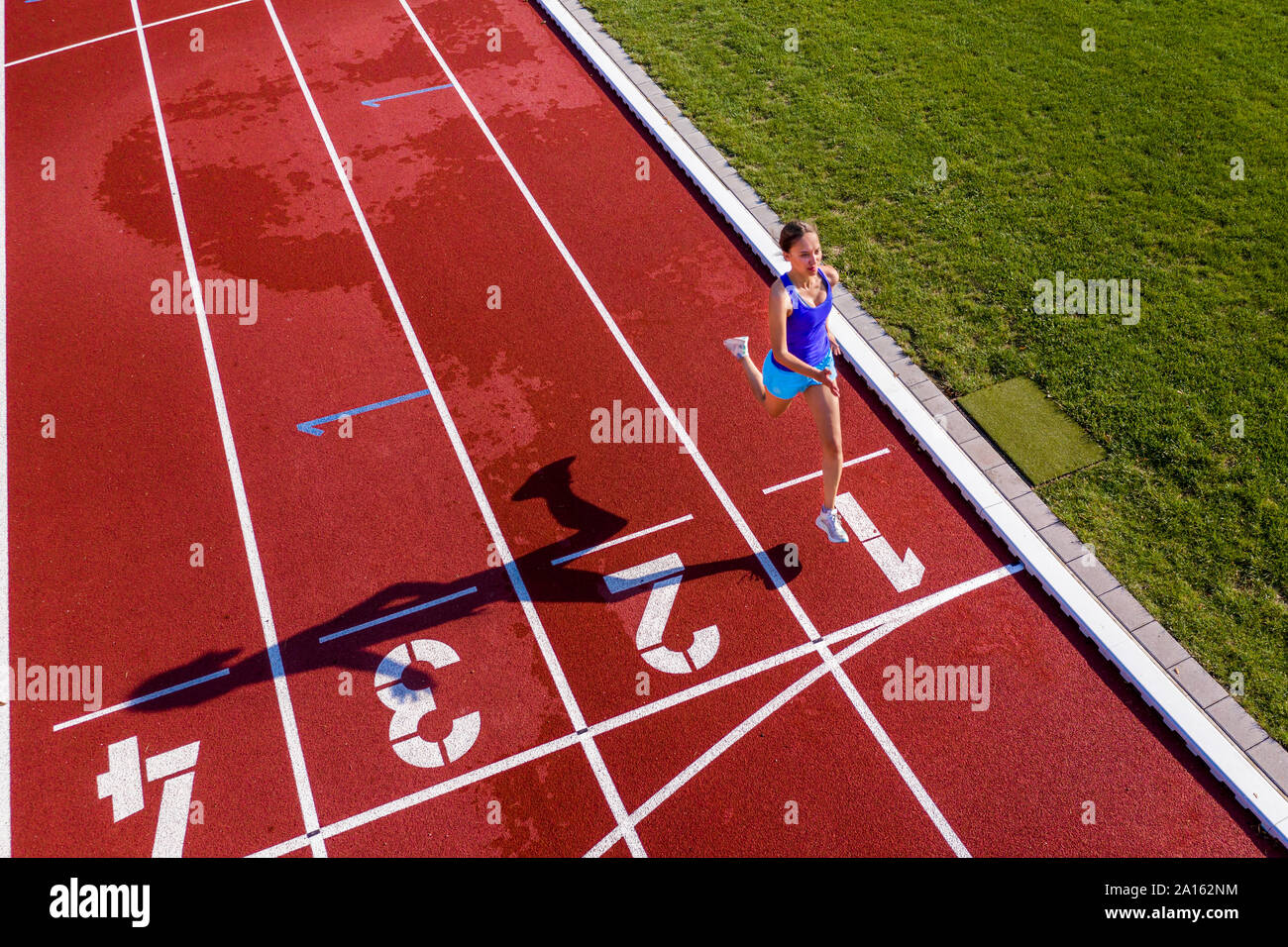 Aerial view of a running young female athlete on a tartan track crossing finishing line Stock Photo