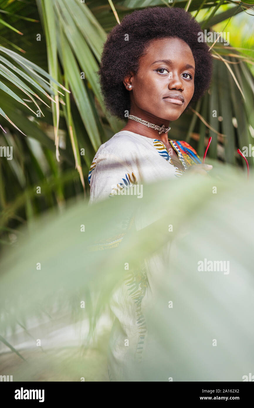 Young woman standing among tropical plants Stock Photo