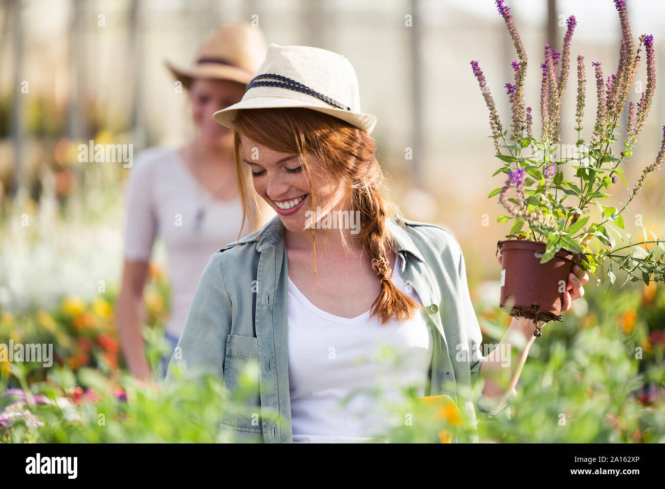 Beautiful young woman taking care of flowers in the greenhouse Stock Photo