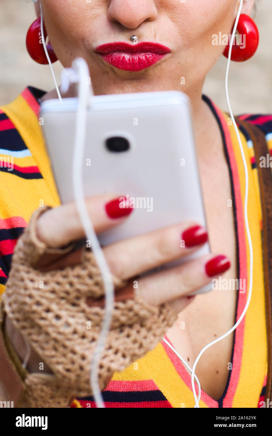 Woman with red lips and piercing using cell phone, close-up Stock Photo