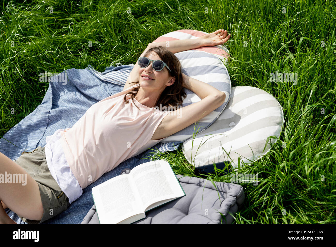 Relaxed woman with book lying on a meadow Stock Photo