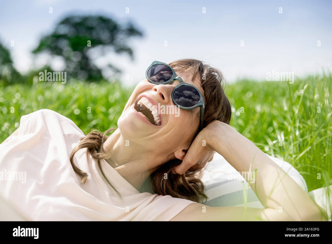 Portrait of laughing relaxed woman lying on a meadow Stock Photo