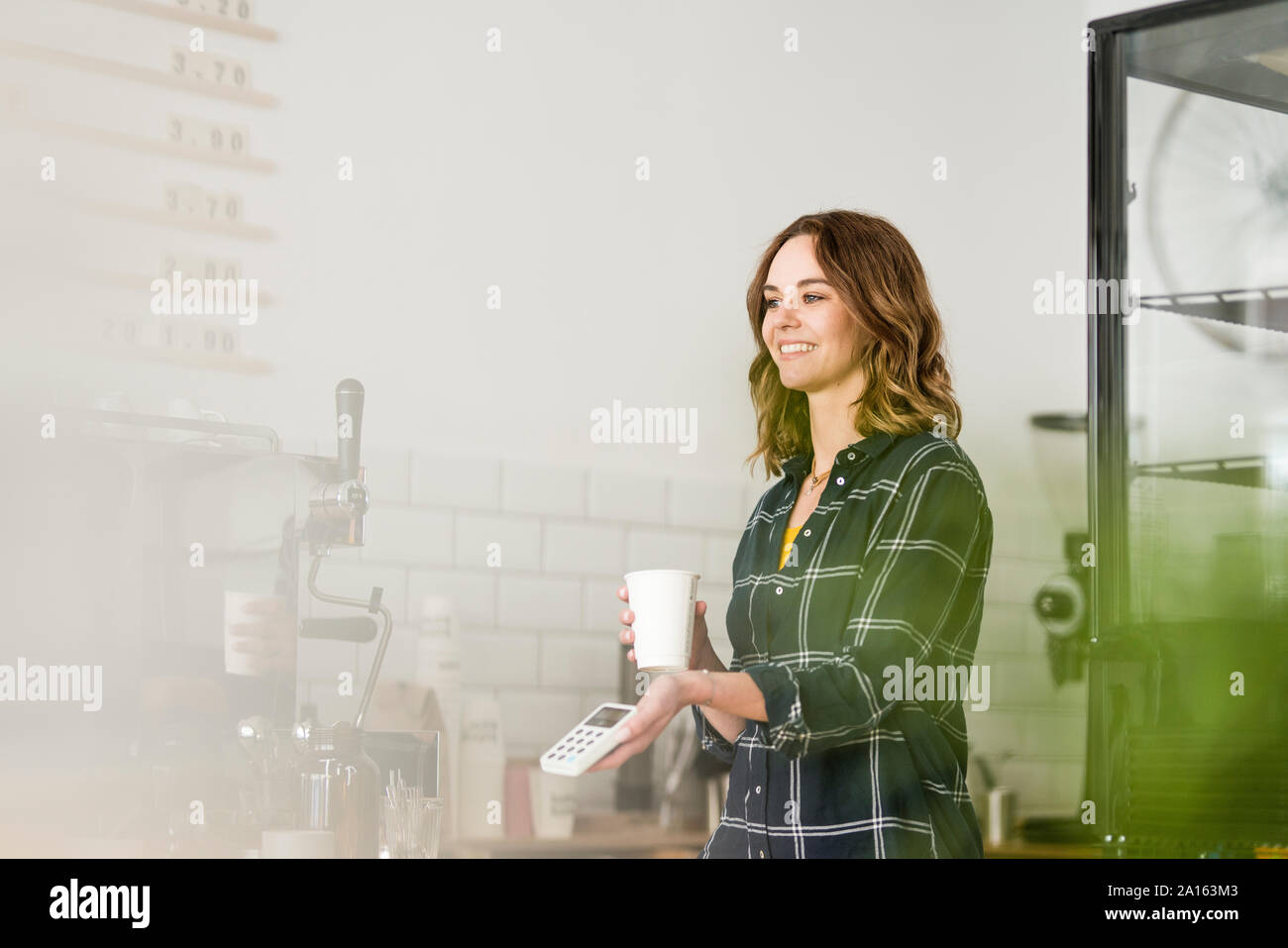 Young woman, working in coffeeshop, offering card reader Stock Photo