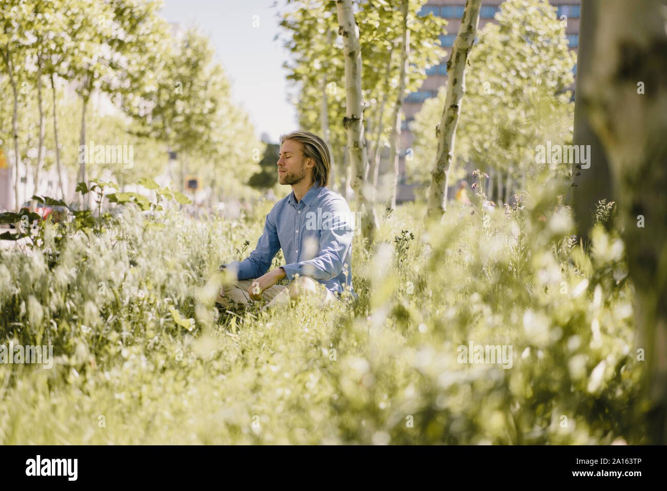 Young man meditating in urban park Stock Photo