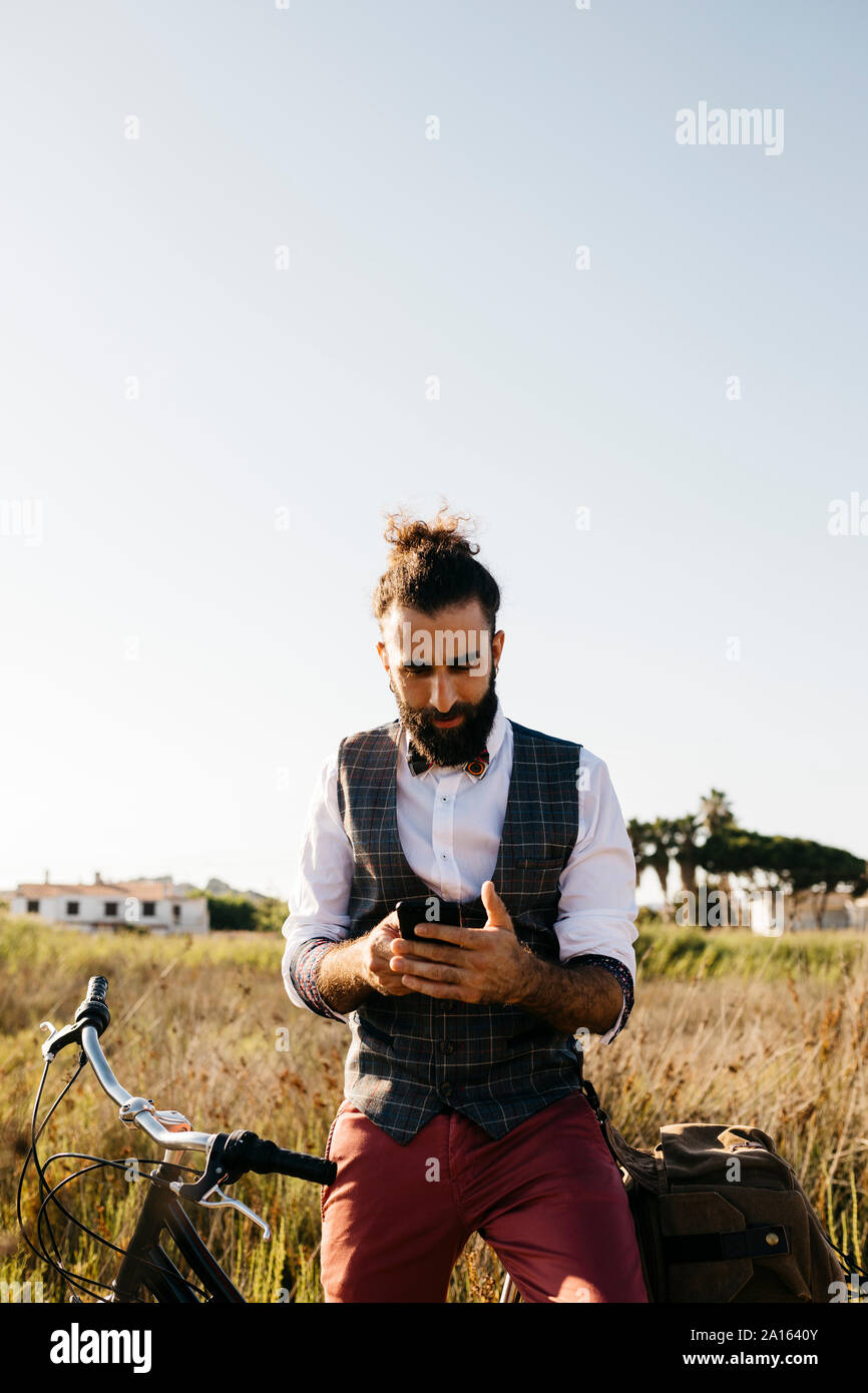 Well dressed man with his bike in the countryside using cell phone Stock Photo