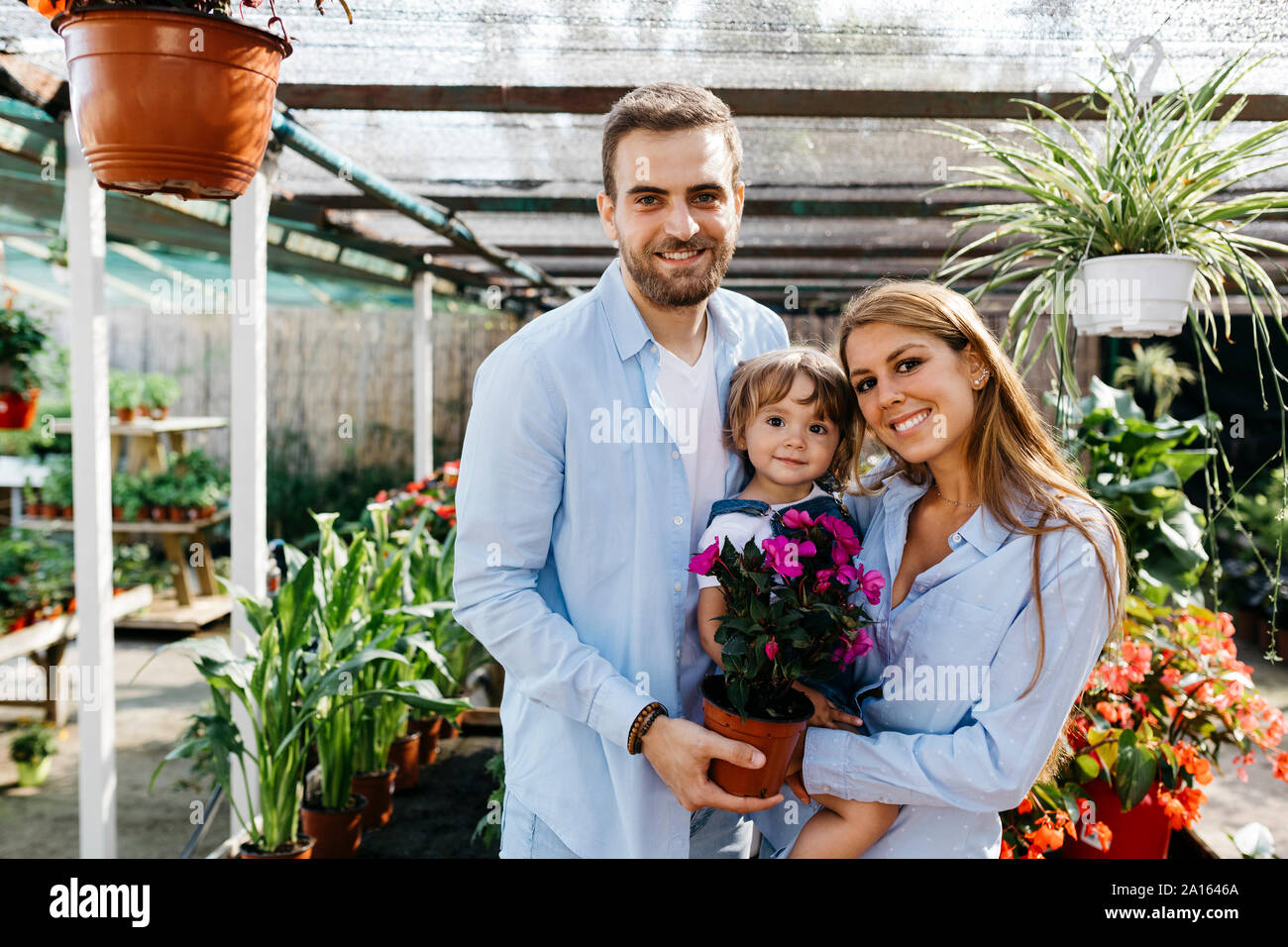 Portrait of happy mother, father and daughter buying flowers in a garden center Stock Photo