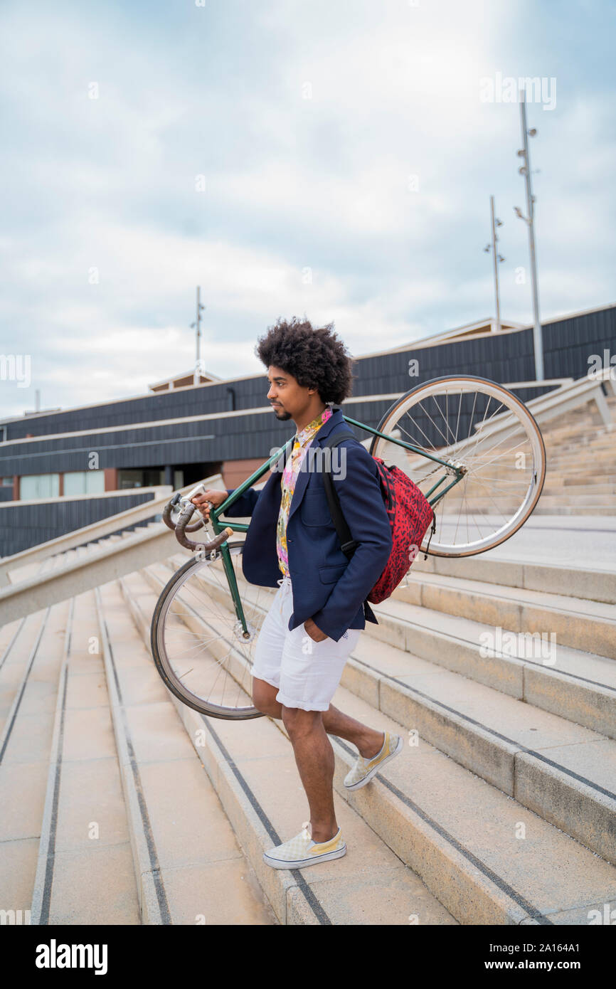 Stylish man carrying bicycle on stairs in the city Stock Photo