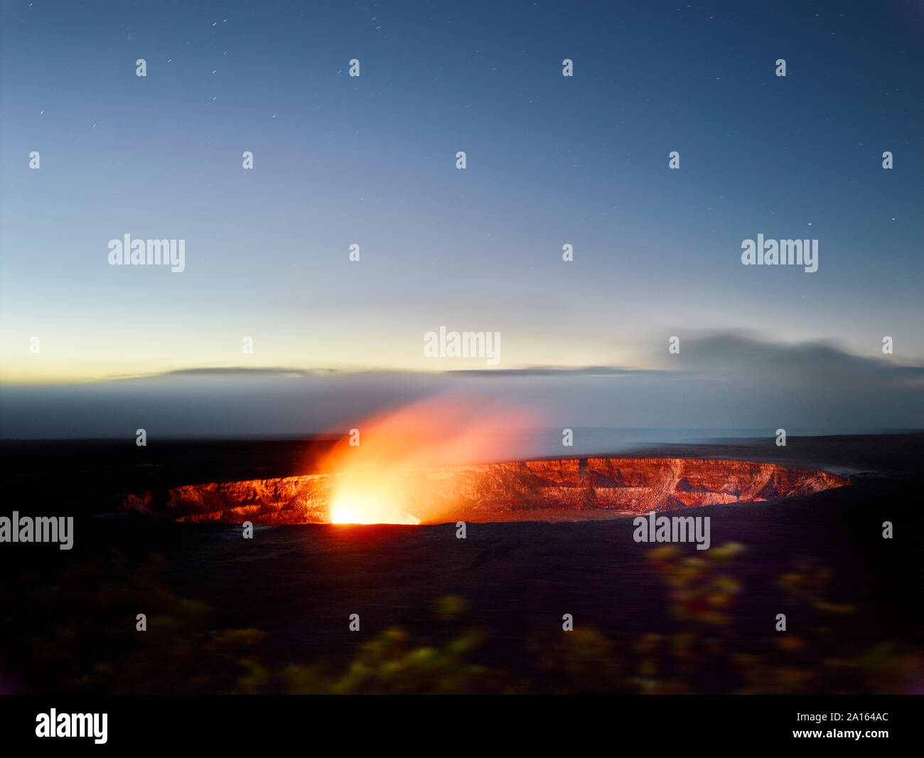 Glowing Halema'uma'u Crater in Hawaii Volcanoes National Park against sky at dusk Stock Photo