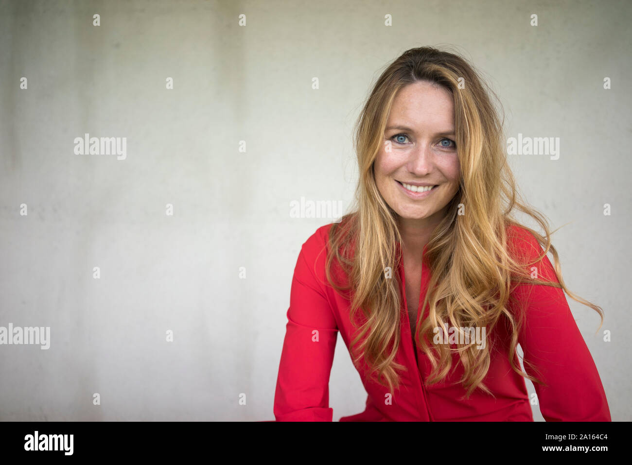 Portrait of smiling woman wearing red jumpsuit Stock Photo