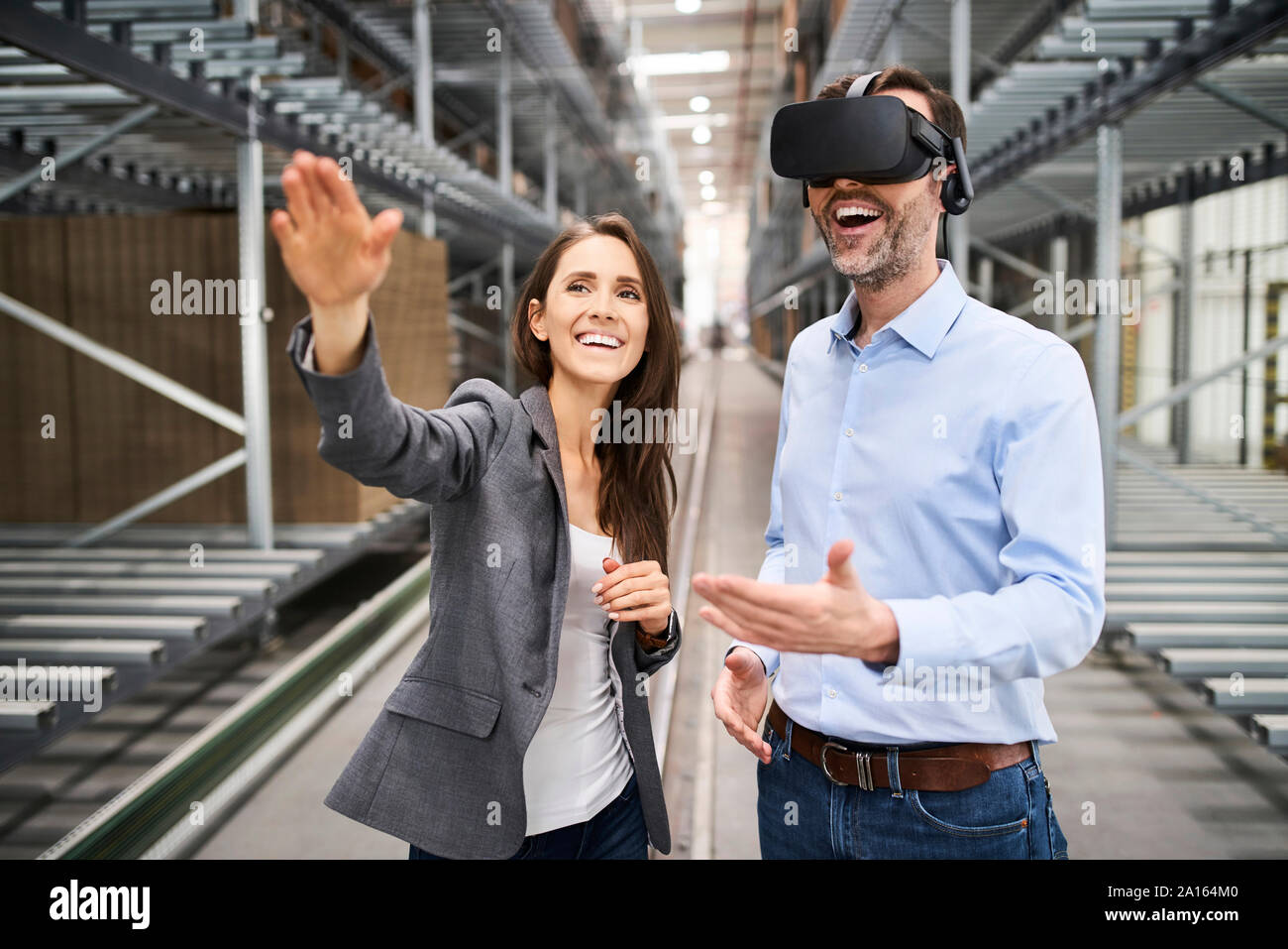 Happy businesswoman and businessman wearing VR glasses in factory Stock Photo