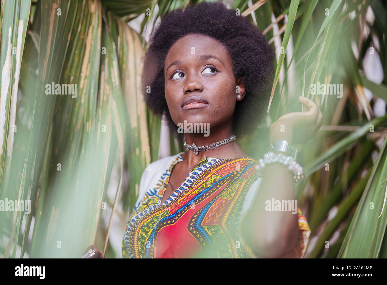 Young woman standing among tropical plants Stock Photo