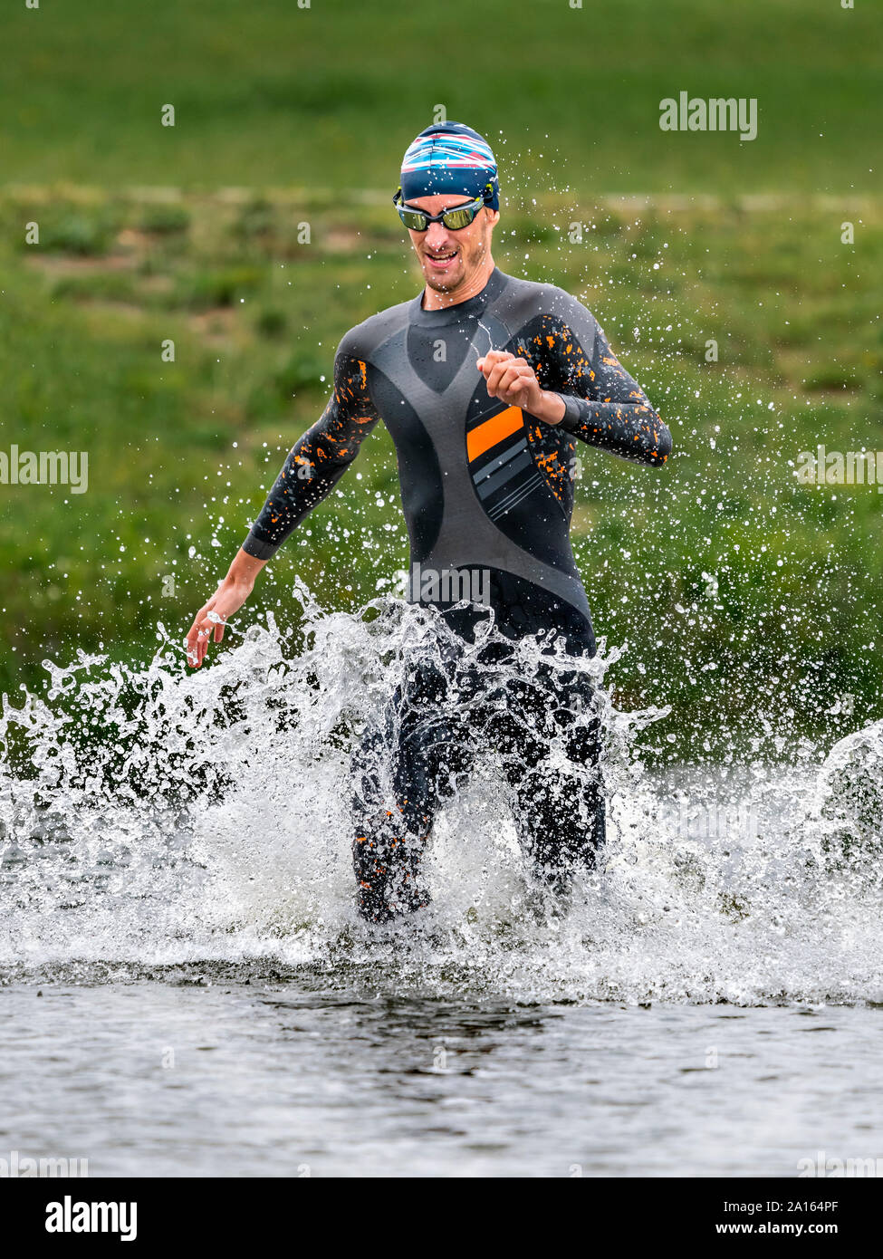 Young triathlete running into a lake Stock Photo