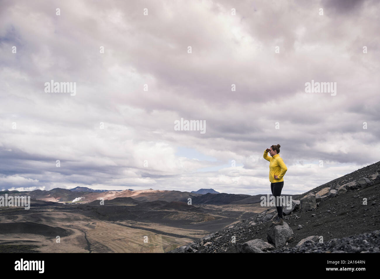 Young woman standing on Hverfjall crater near Myvatn, Iceland, looking at view Stock Photo