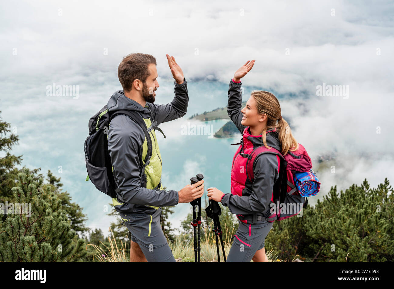 Happy young couple on a hiking trip in the mountains high fiving, Herzogstand, Bavaria, Germany Stock Photo