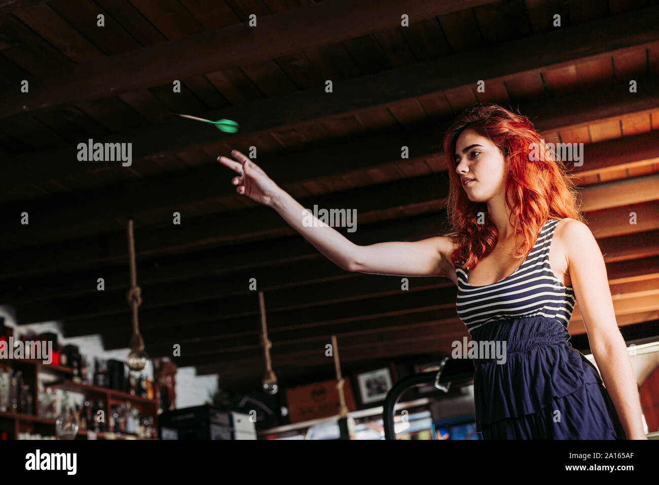 Young woman playing darts in a sports bar Stock Photo