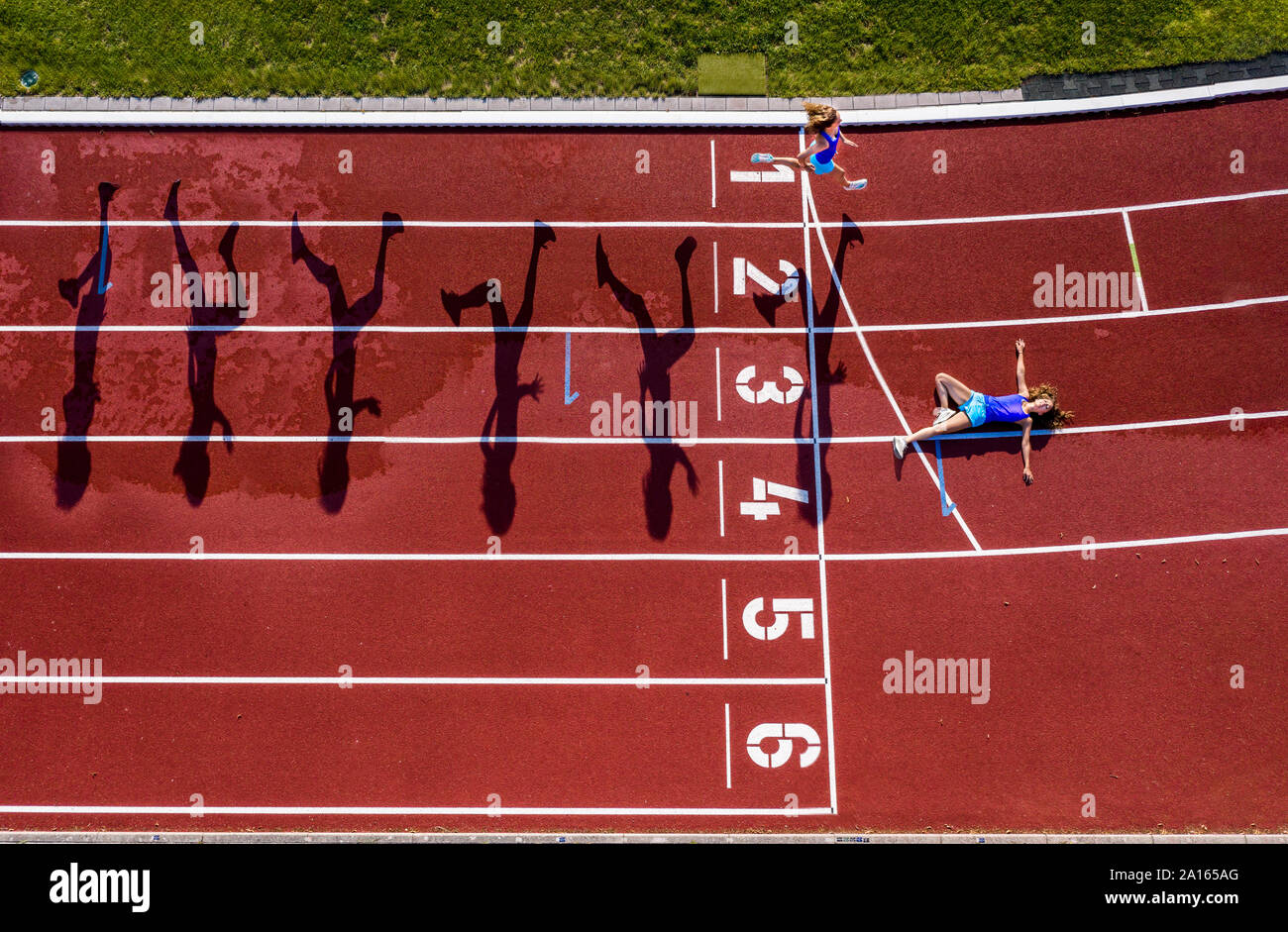 Aerial view of a running and lying young female athlete on a tartan track Stock Photo