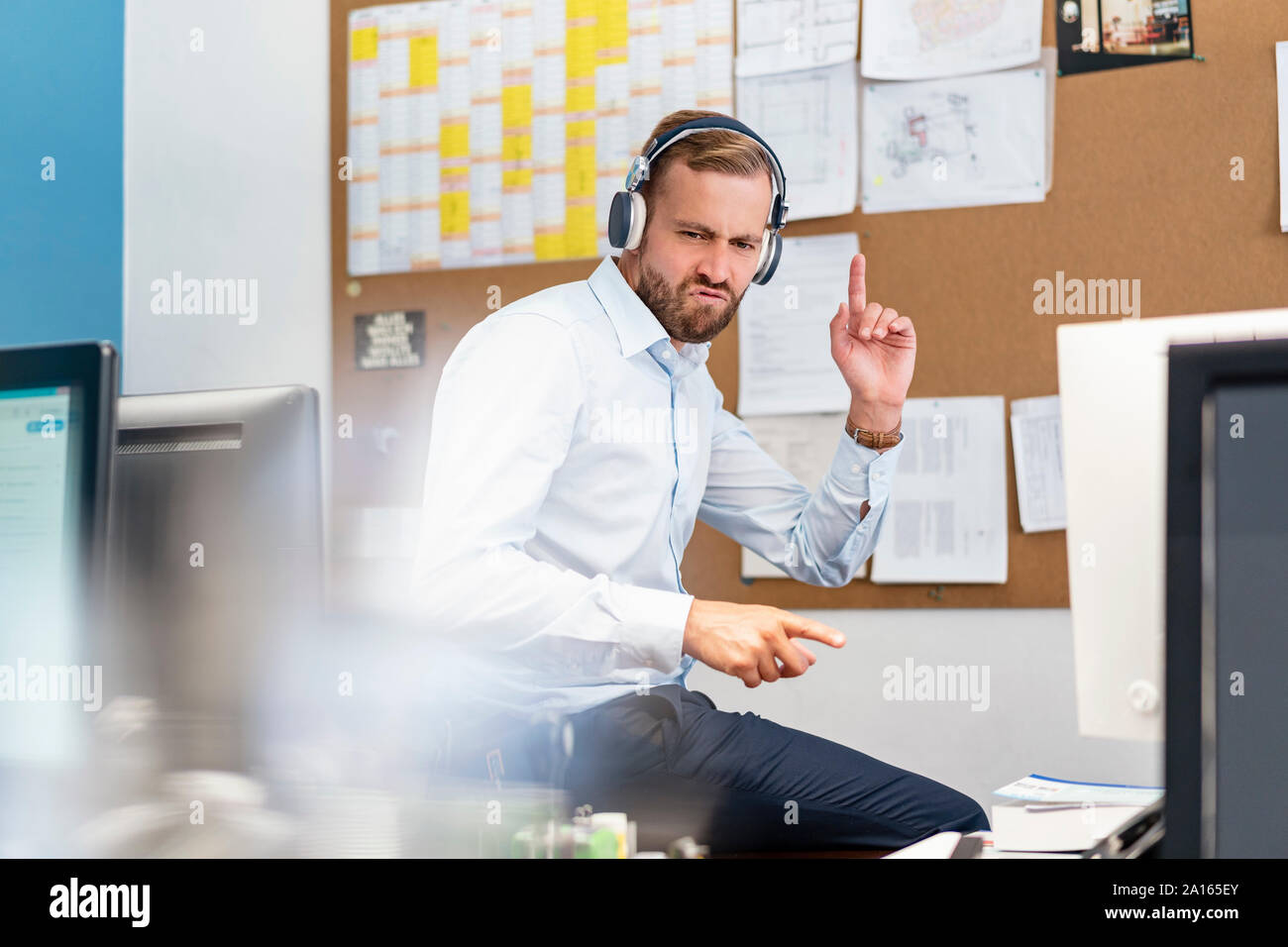 Businessman listening to music with headphones in office Stock Photo