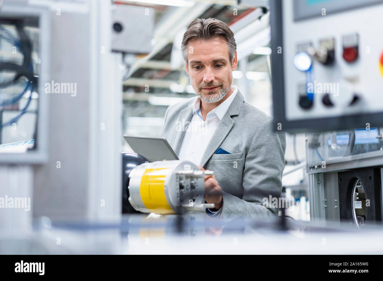 Businessman with tablet at assembly robot in a factory Stock Photo