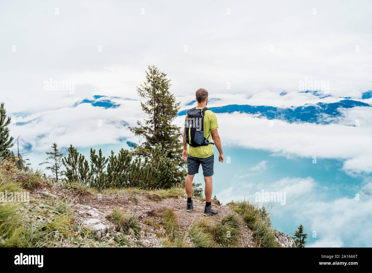 Young man on a hiking trip in the mountains looking at view, Herzogstand, Bavaria, Germany Stock Photo