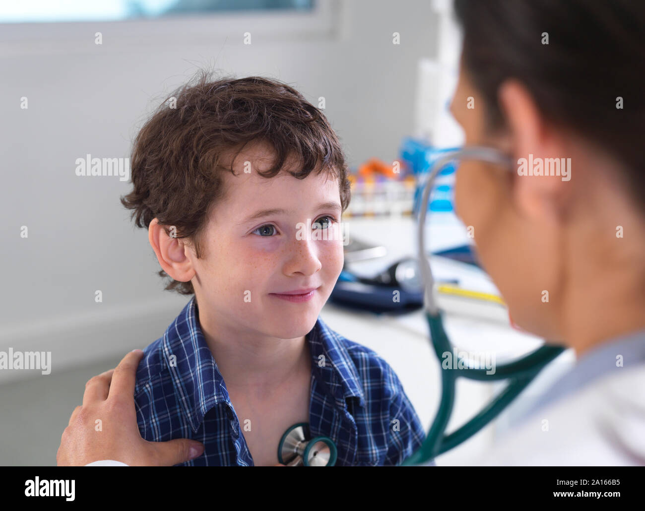 Female doctor examiming a boy using a stethoscope Stock Photo