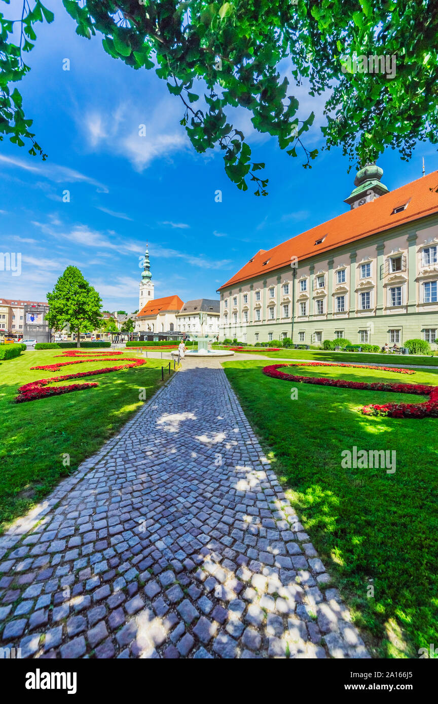 Austria, Carinthia, Klagenfurt am Worthersee, Garden and Church of the Holy Ghost on sunny day Stock Photo