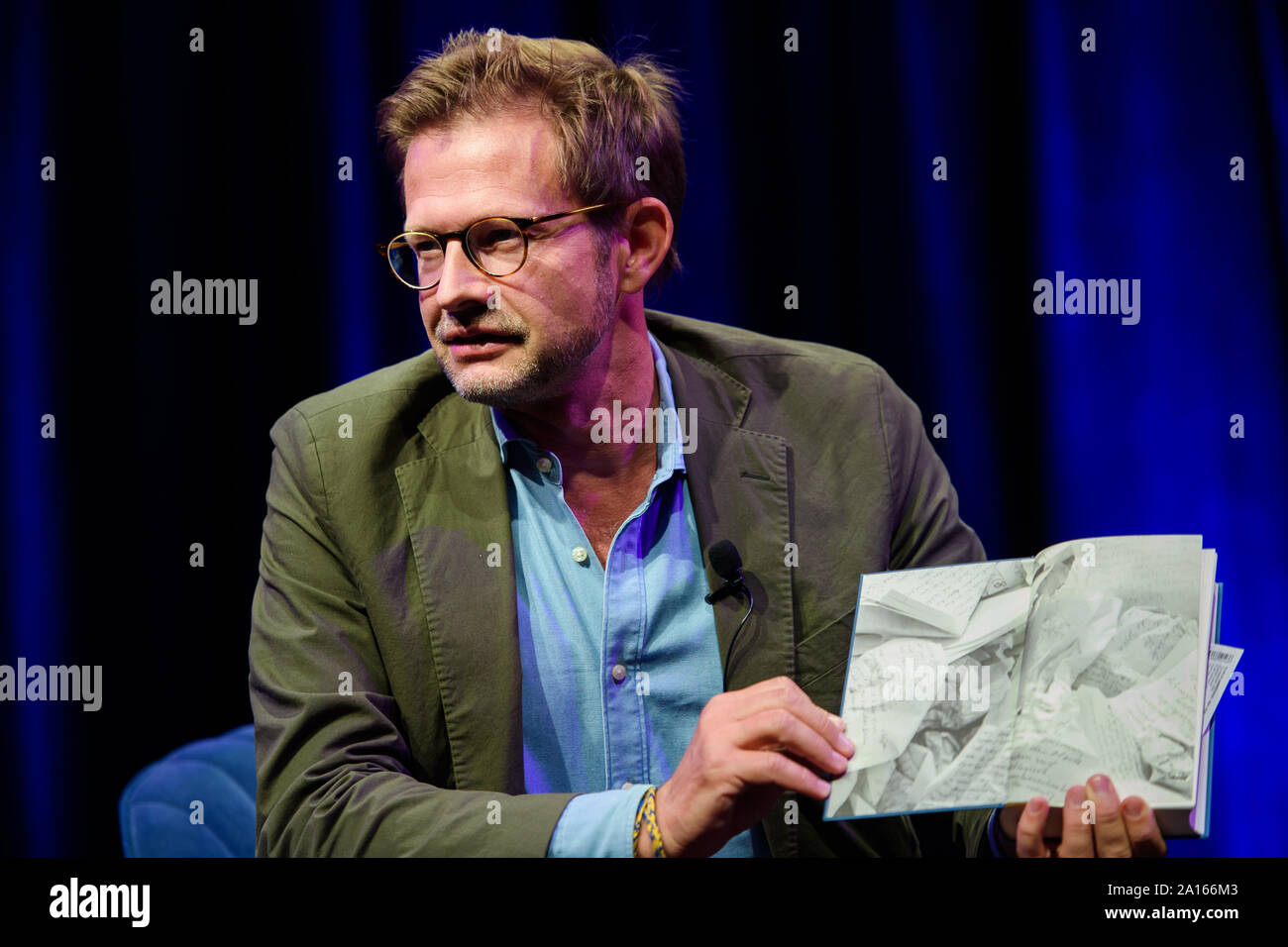 23 September 2019, Berlin: Florian Illies, managing publisher of Rowohlt Verlag, holds the book on stage during the presentation of the autobiography of fashion designer Wolfgang Joop "Die einzig mögliche Zeit" in the tipi at the Chancellery. Photo: Gregor Fischer/dpa Stock Photo