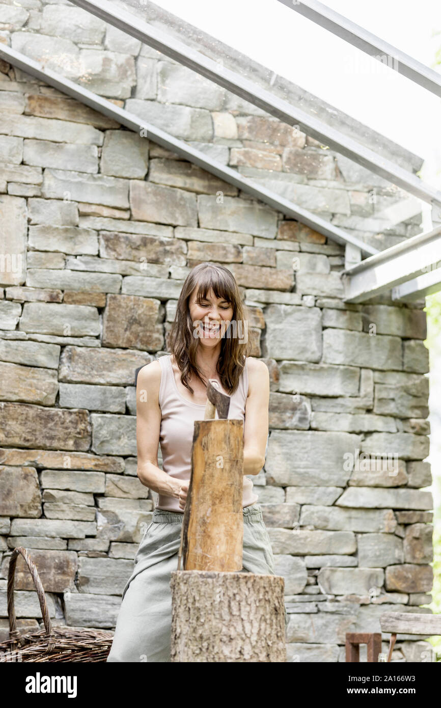 Screaming woman chopping wood in front of a house Stock Photo
