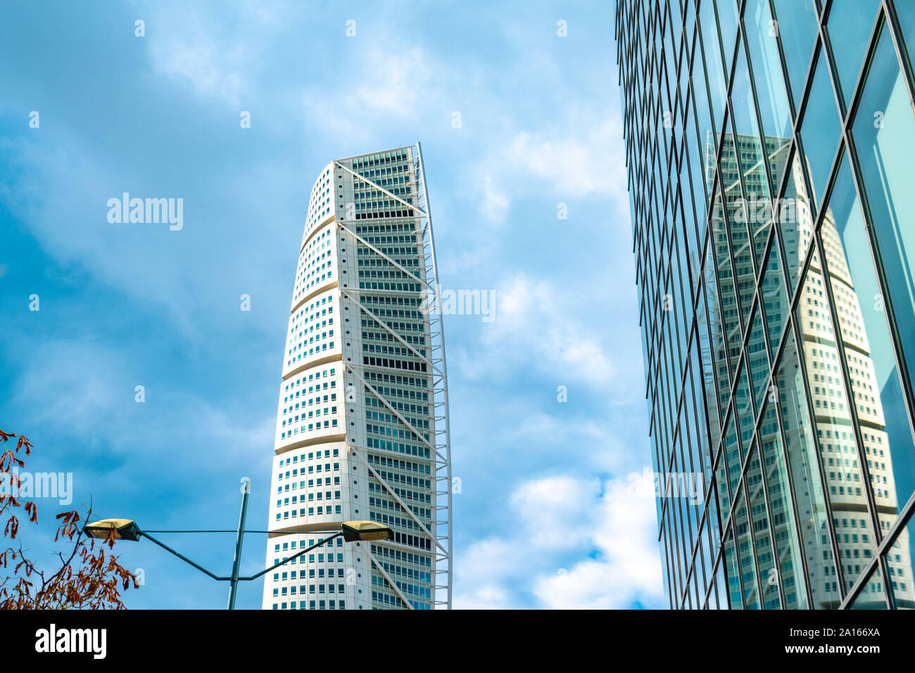 Low angle view of turning torso tower reflecting on glass building against sky Stock Photo
