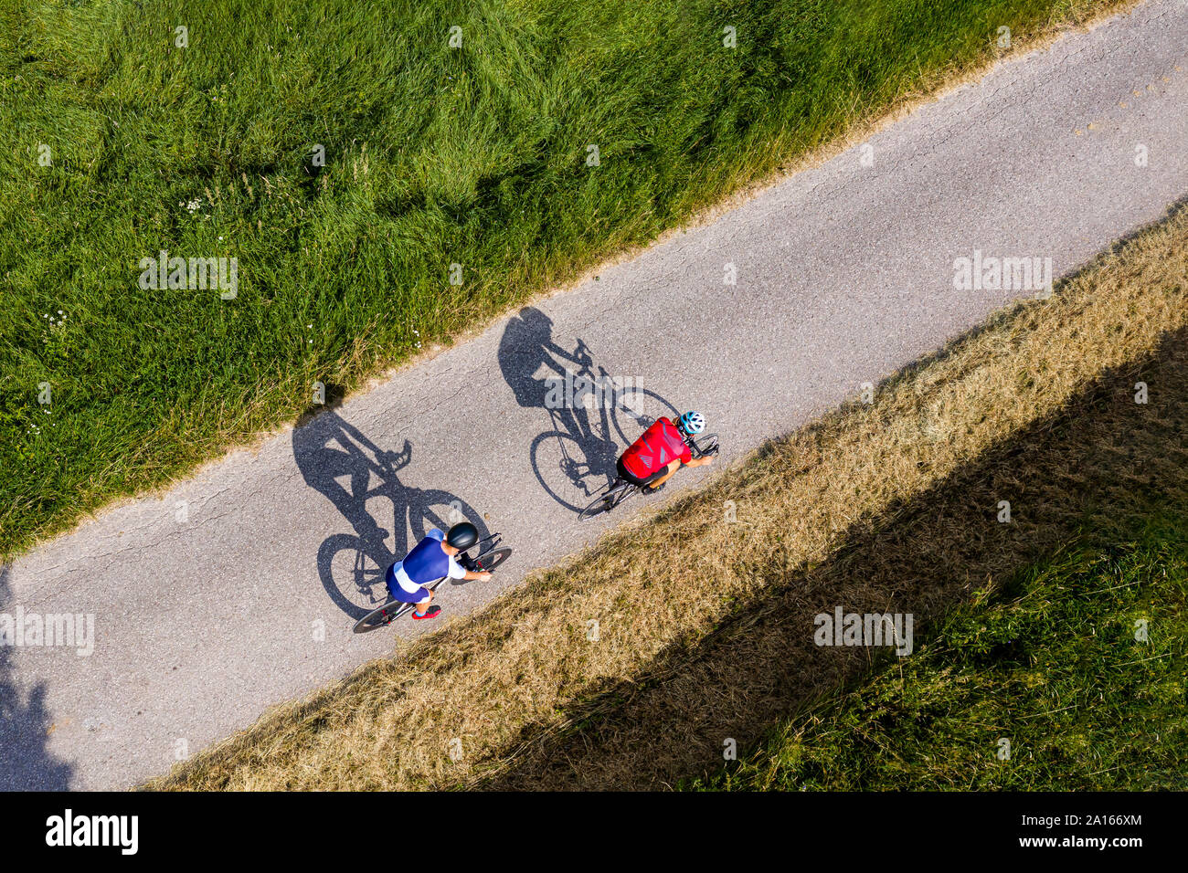 Triathletes riding bicycle on country road, Germany Stock Photo