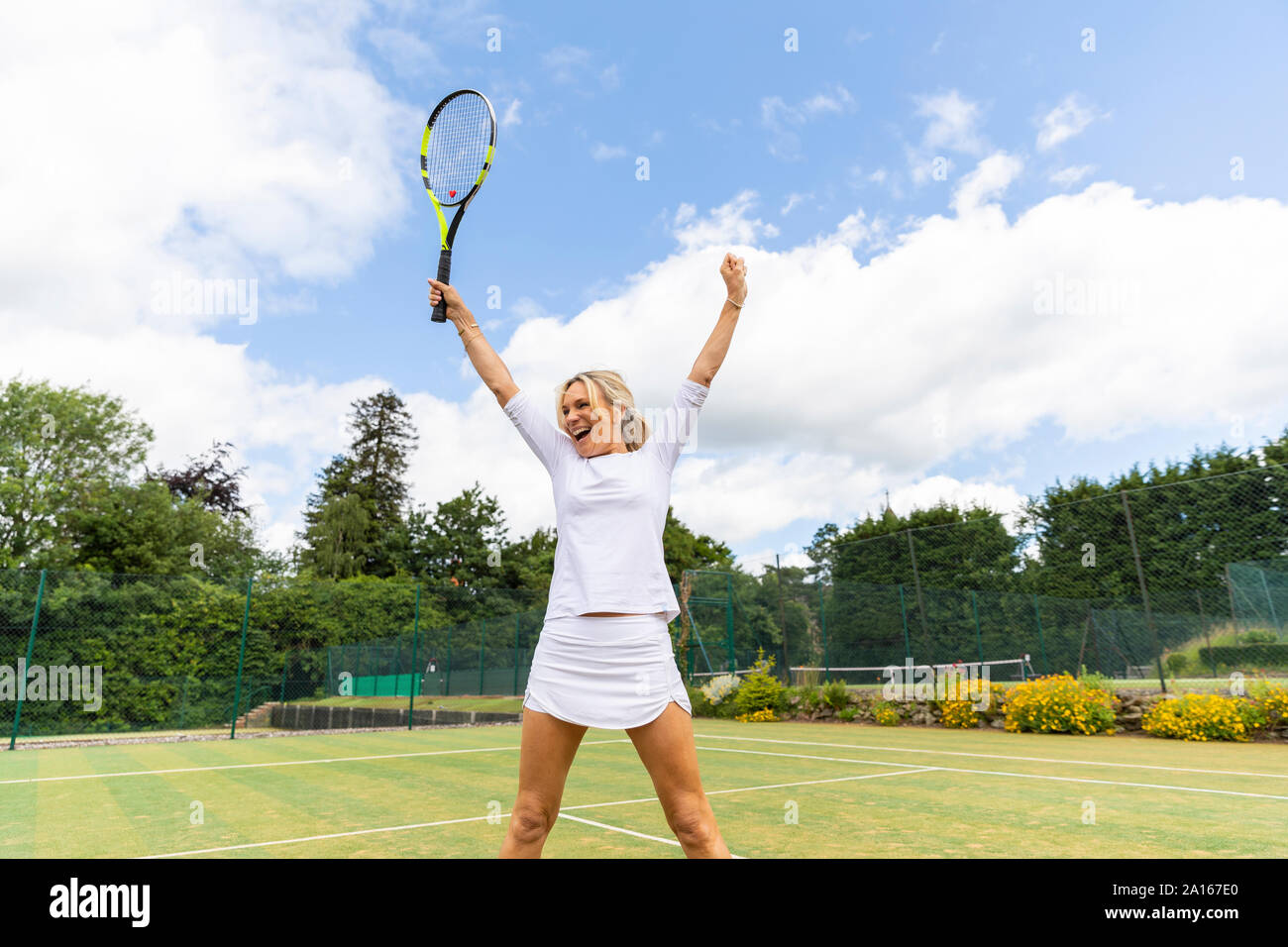 Happy female tennis player celebrating the victory on grass court Stock Photo