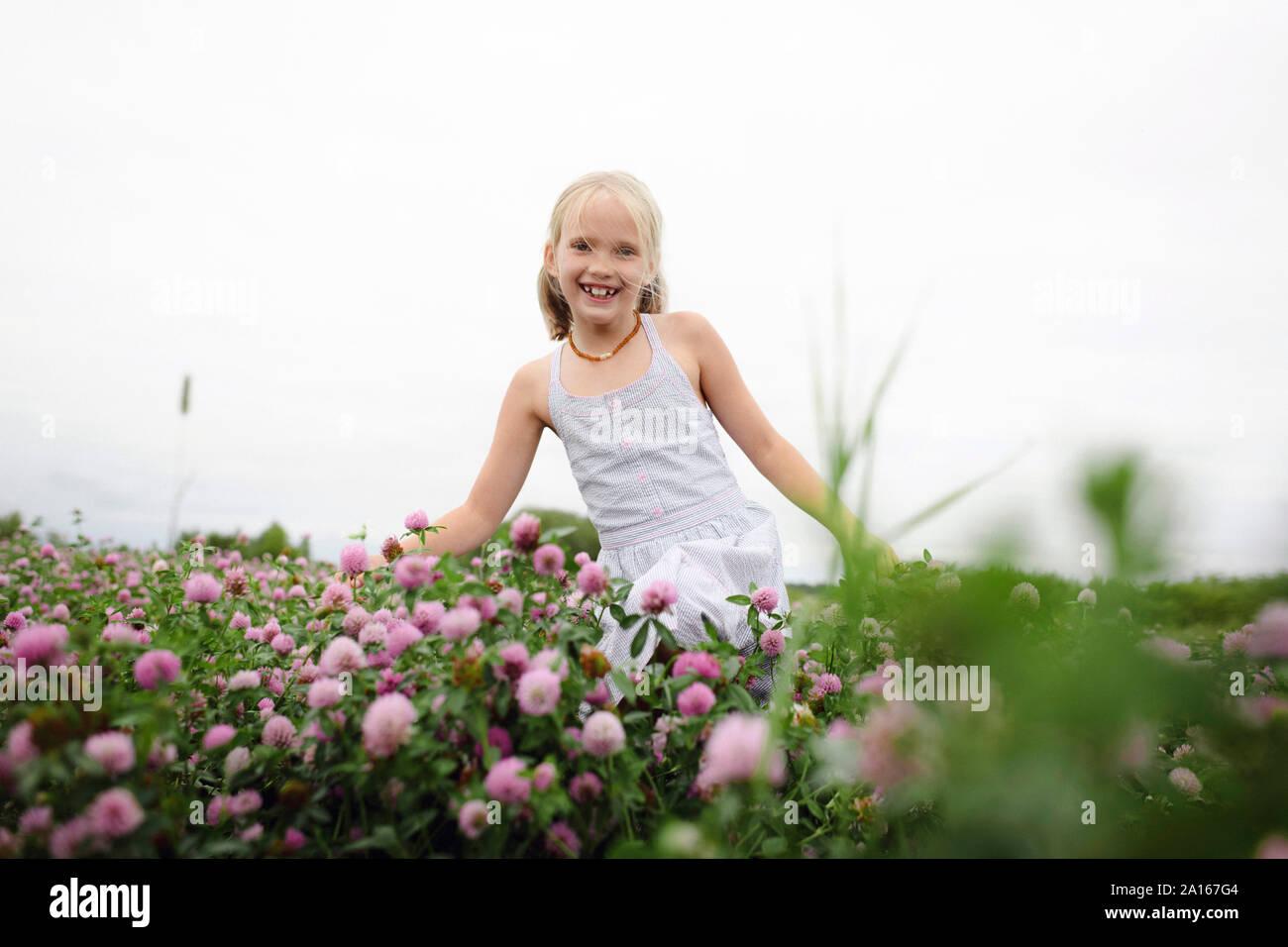 Smiling girl with bunches running on clover field Stock Photo