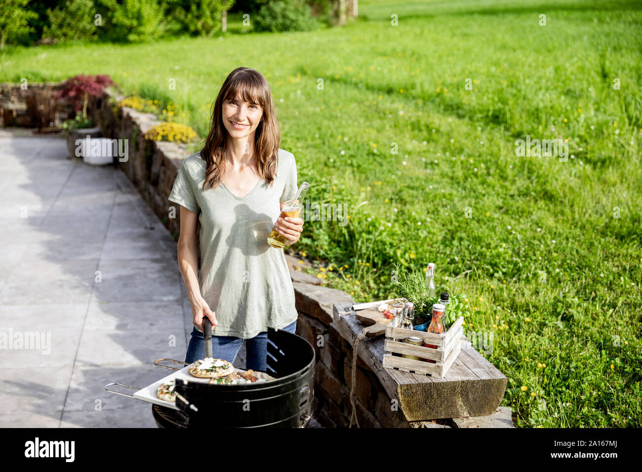 Portrait of smiling woman preparing food on barbecue grill Stock Photo