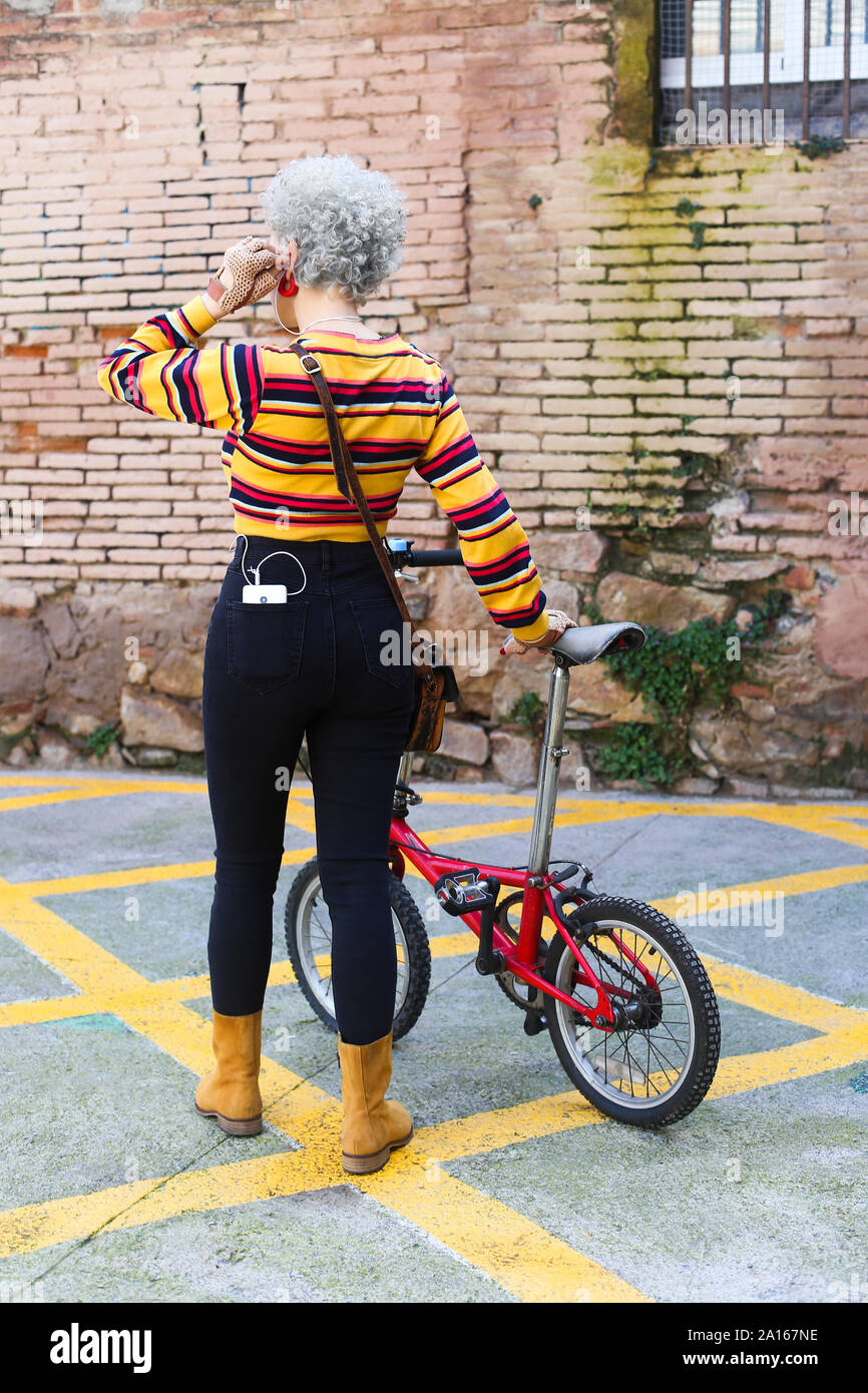 Back view of woman with bicycle carrying smartphone in her pocket Stock Photo