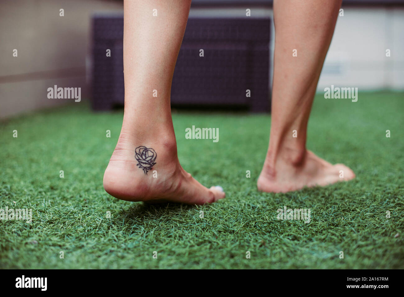 Close-up of a woman's tattooed foot walking on artificial grass Stock Photo