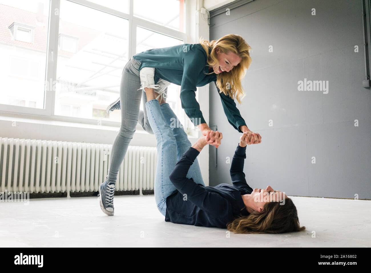 Two young women supporting each other playfully Stock Photo