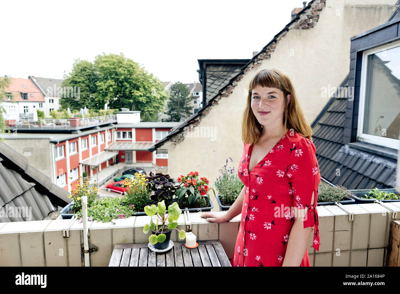 Portrait of smiling young woman standing on balcony Stock Photo