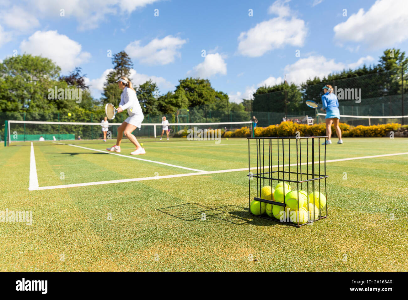 Mature women playing tennis on grass court Stock Photo