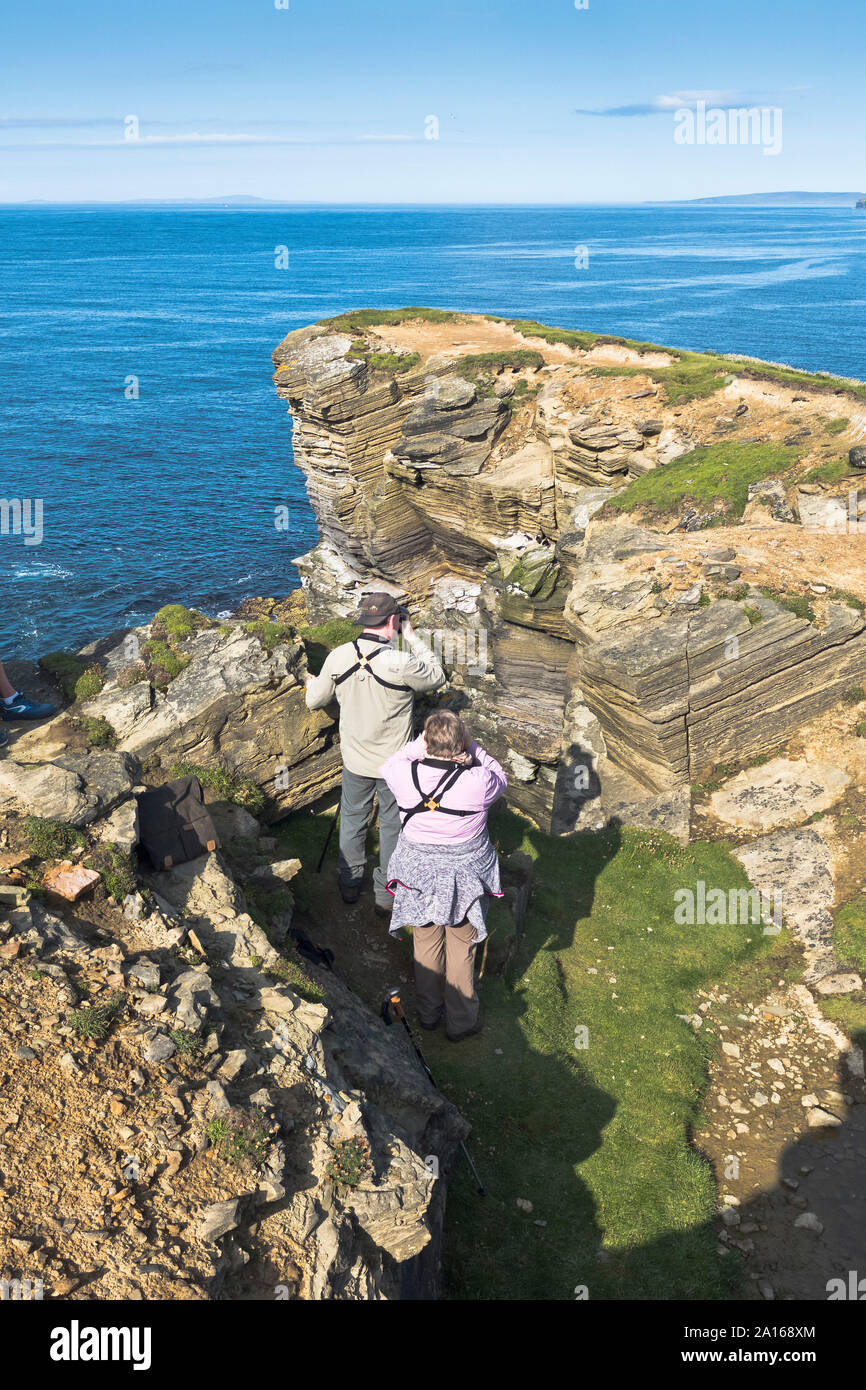 dh Brough of Birsay BIRSAY ORKNEY Couple watching photographing puffins tourists scotland puffin fratercula arctica people Stock Photo