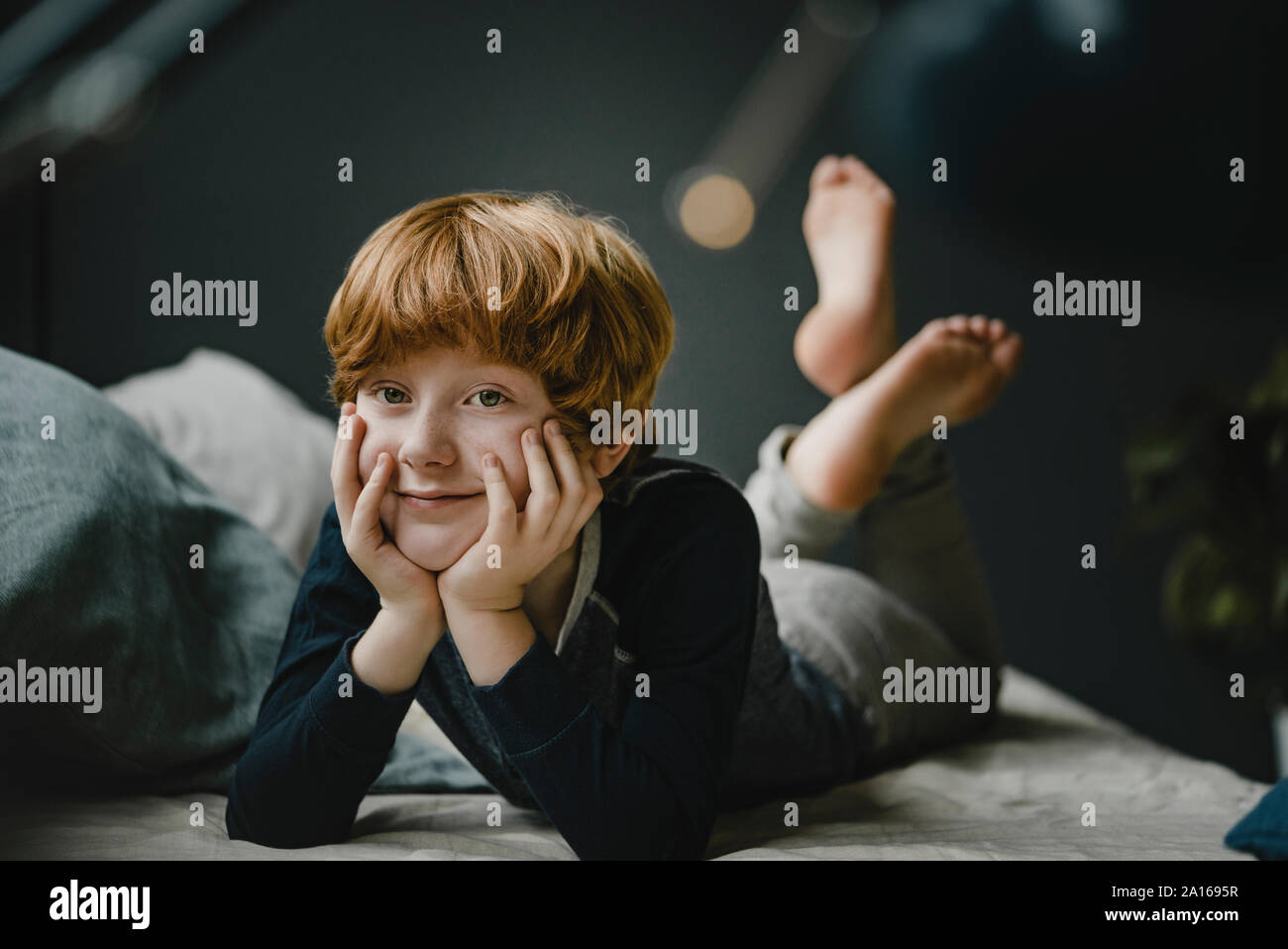 Portrait of smiling redheaded boy lying on couch at home Stock Photo