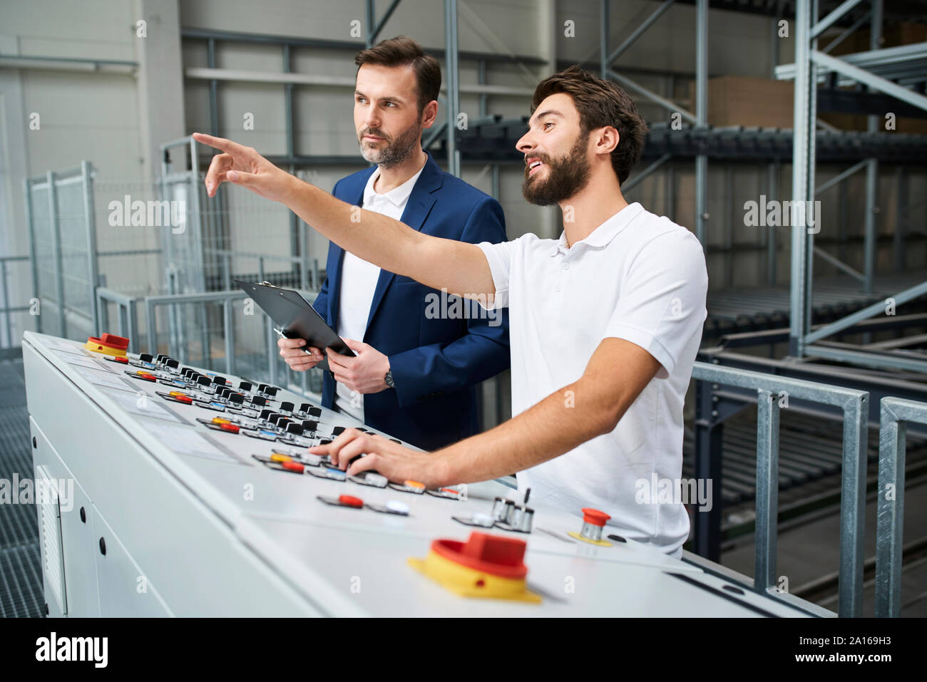 Businessman and employee talking at control panel in a factory Stock Photo