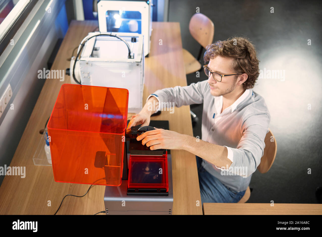 Technician sitting at table with 3D printer Stock Photo